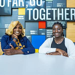 Assistant Professor Amanda Wilkerson, left, and educational leadership alumna Ashley Samson sit together at a table at UCF Downtown, smiling.